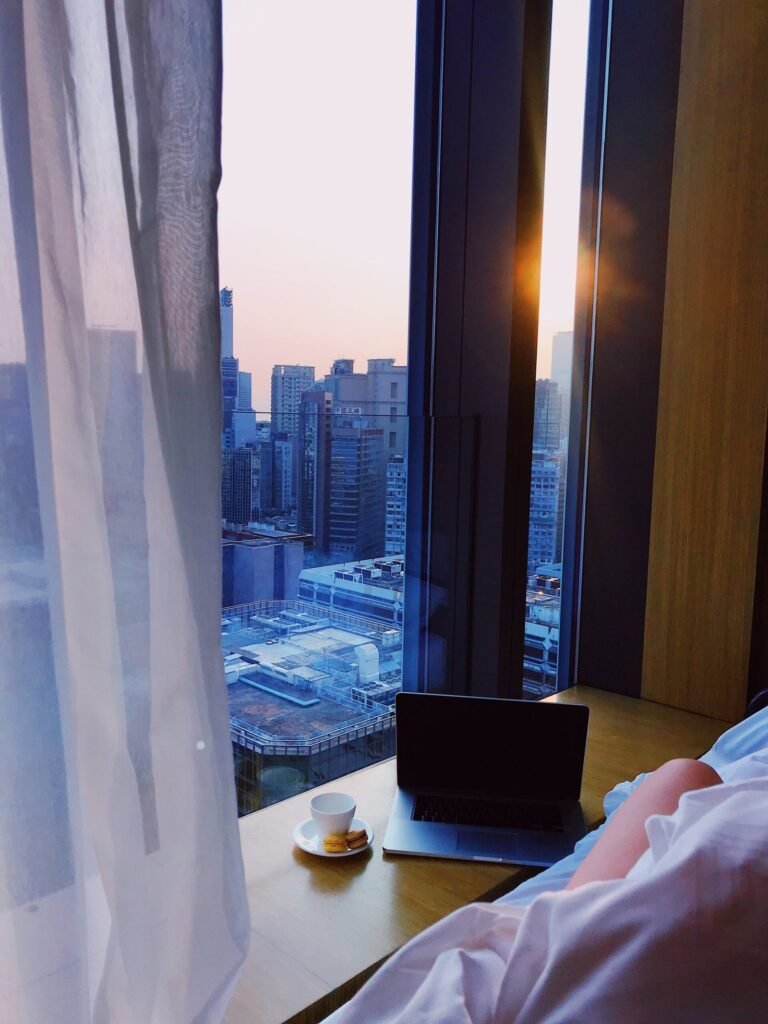 Computer portatile su un tavolino accanto a una finestra sulla città al tramonto